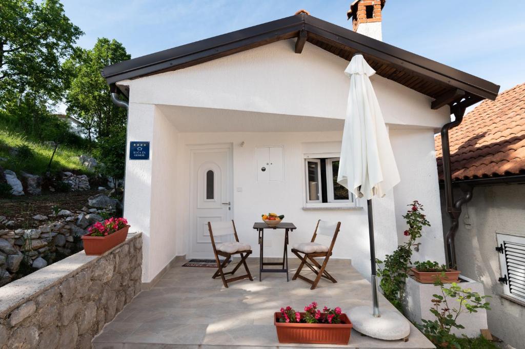 una casa bianca con tavolo, sedie e ombrellone di Kuca za odmor NALL a Lovran (Laurana)