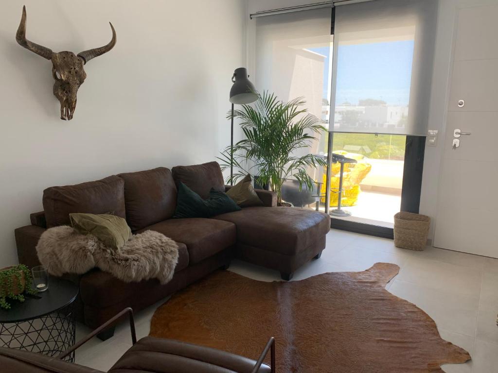a living room with a brown couch and a table at Penthouse Las 2 Salchichas in San Javier