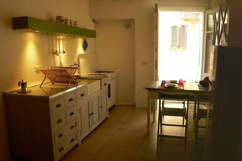 a kitchen with white cabinets and a table and a window at L'Approdo Bilocale in Carloforte