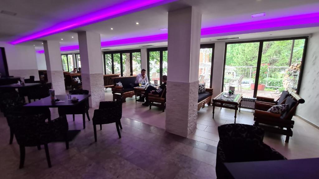 a restaurant with purple lighting in a room with tables and chairs at Hotel Royal Drina in Mali Zvornik