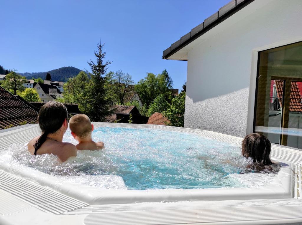 eine Familie spielt in einer Whirlpool-Badewanne in einem Haus in der Unterkunft Wellness Hotel Garni Krone in Baiersbronn