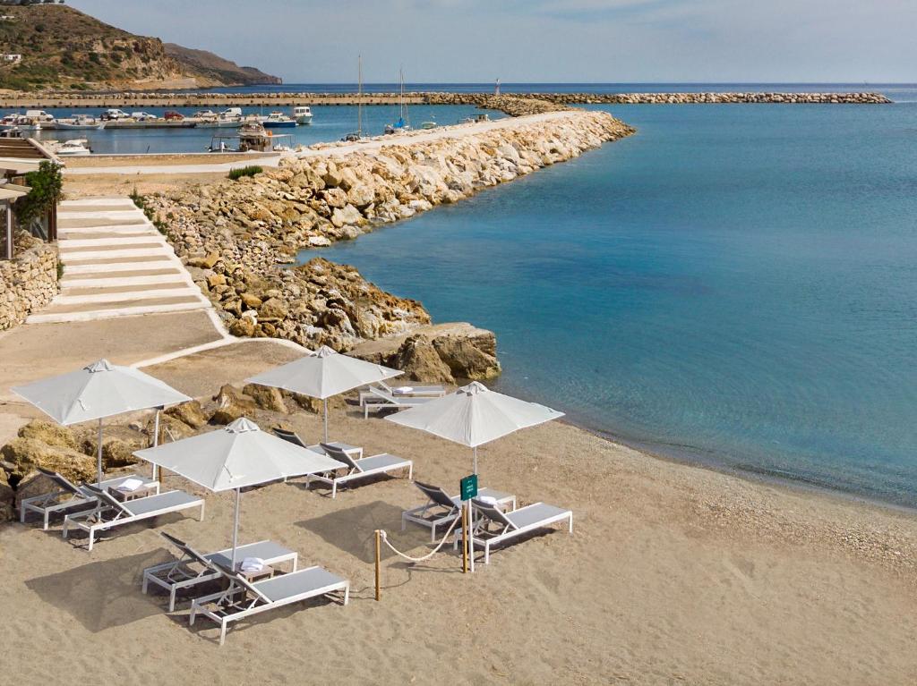 a beach with chairs and umbrellas and the water at Kolymbari Sea Front Cozy Apartments in Kolymvari