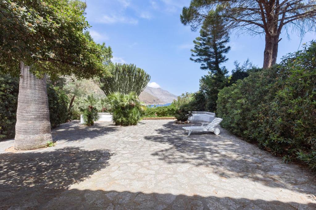 a bench sitting in the middle of a garden at Scopello Flat with Panoramic Courtyard and Parking in Scopello