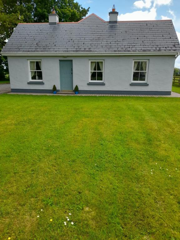 una casa blanca con un gran césped delante de ella en Katy Kellys Countryside Self Catering Cottage en Roscommon