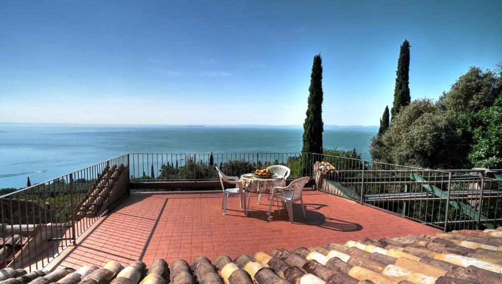 une terrasse avec une table et des chaises et l'océan dans l'établissement Villa in the green, extraordinary silent position, great lake view, à Garde
