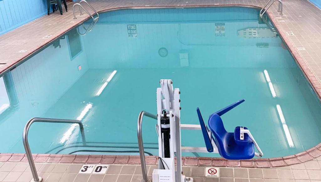 - une piscine avec une chaise dans l'eau dans l'établissement Magnuson Hotel Country Inn, à Ishpeming