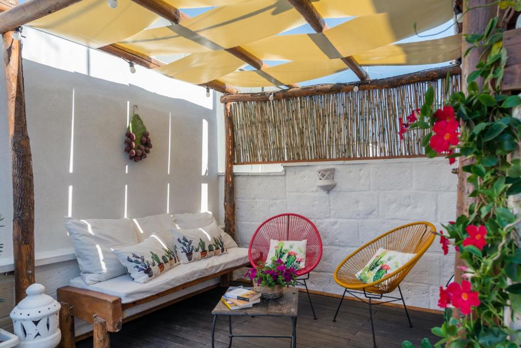 eine Veranda mit einem Sofa, Stühlen und Blumen in der Unterkunft CIVETTHOUSE : la casa delle civette in Polignano a Mare