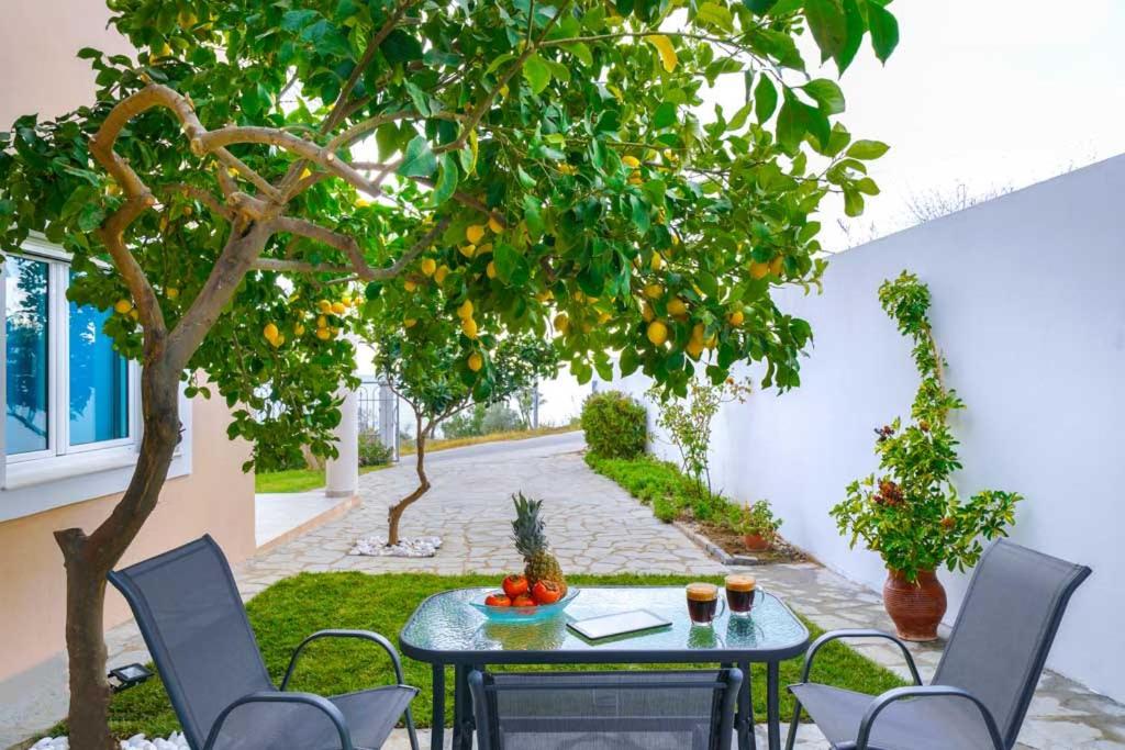 a patio with a table and chairs under an orange tree at El Mare Seaside Retreats - Bespoke Luxury Getaways in Limenaria