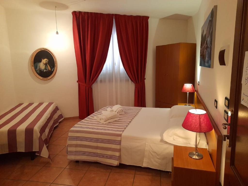 - une chambre avec un lit et une fenêtre avec des rideaux rouges dans l'établissement 8380 camere Mastro, à Montemerano