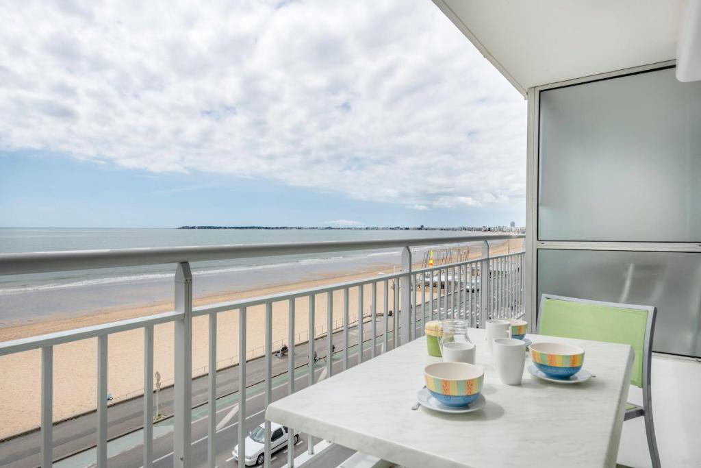 un balcon avec une table et des chaises et une vue sur la plage dans l'établissement À 50m de la plage, appartement vue mer pour 5, à Pornichet
