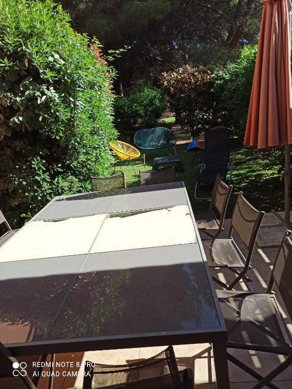 una mesa con sillas y una sombrilla en un patio en CARRO PROCHE MER MAISON DANS RESIDENCE 3 étoiles avec piscine et tennis, en Martigues