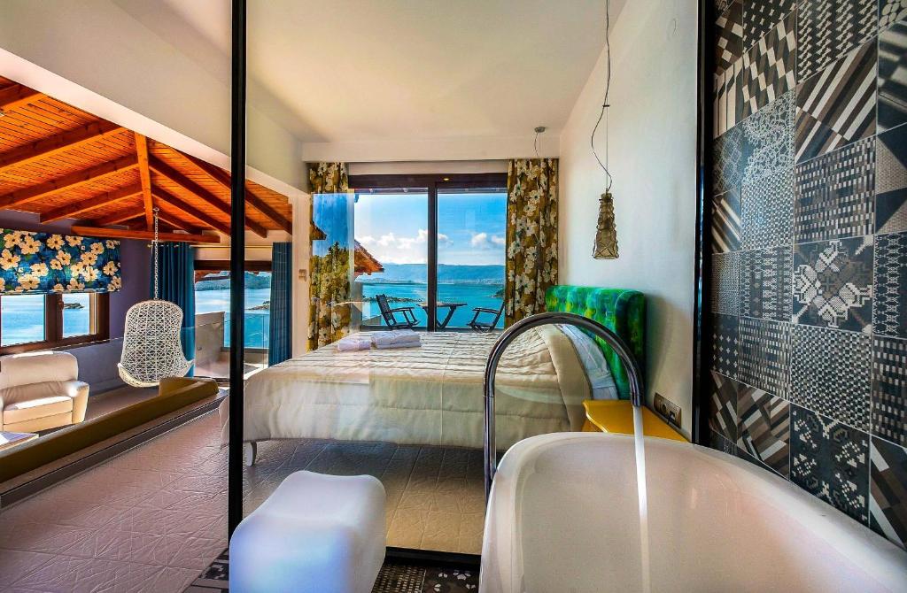 a bathroom with a tub and a bedroom with the ocean at Thalassokipos in Vourvourou