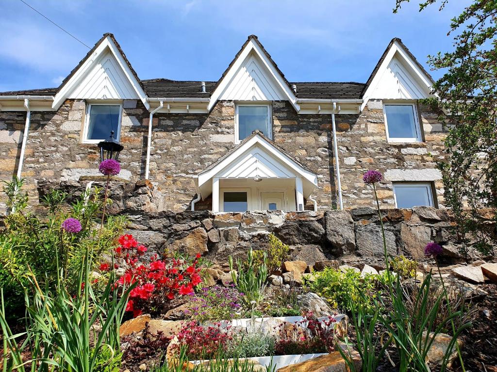 uma casa de pedra com flores em frente em Elmwood House em Pitlochry