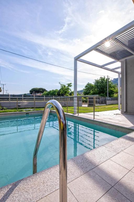 a swimming pool with a metal hand rail next to it at AG Luxury Villas, Iraklitsa in Iraklitsa