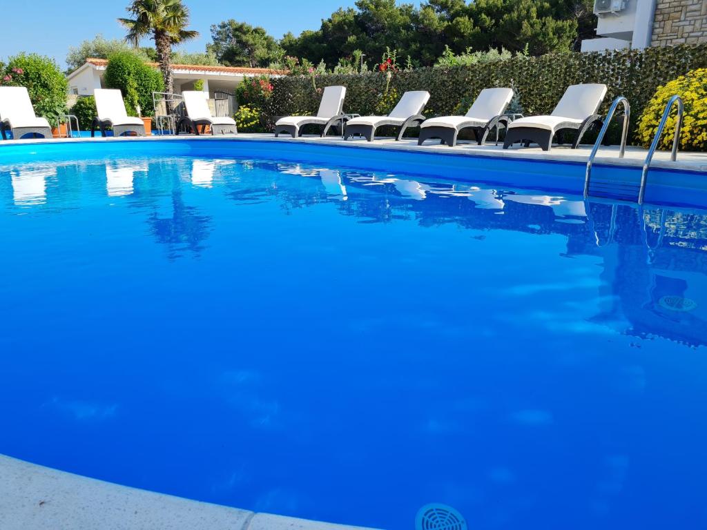 una piscina con sillas y agua azul en Apartments Dorotea, en Novalja