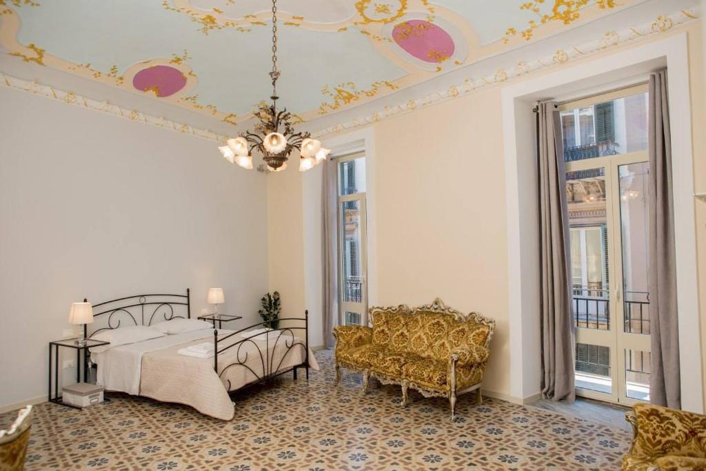 1 dormitorio con 1 cama, 1 silla y ventanas en Calamarina Centro, en Palermo
