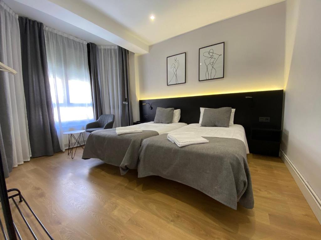 a hotel room with two beds and a chair at Apartamento céntrico Logroño Confort con Aire Acondicionado in Logroño