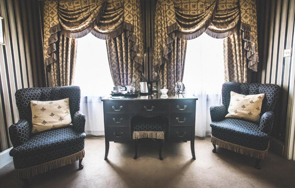 two chairs and a desk in a room with curtains at Jeakes House in Rye