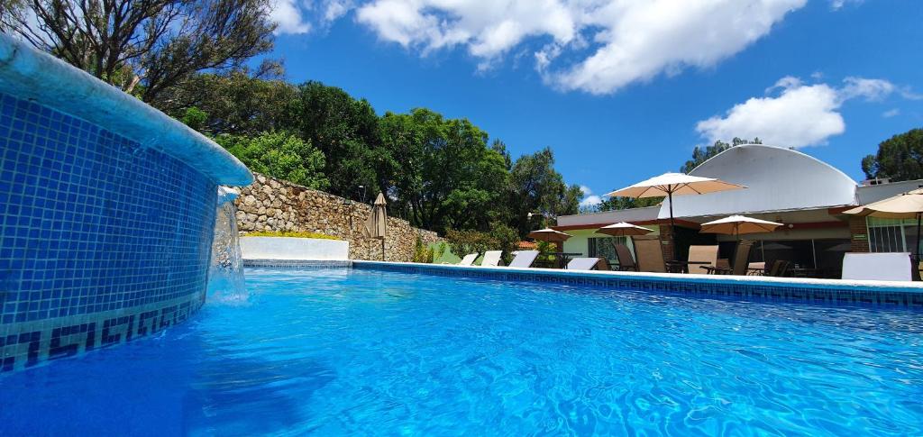 una piscina azul con sillas y sombrillas en Victoria Hotel y Spa en Ixtapan de la Sal