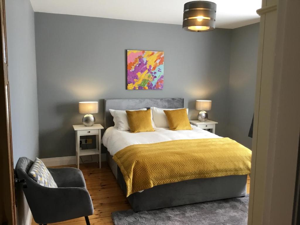 Un dormitorio con una cama con almohadas amarillas y una silla en Knockaguilla House Bed & Breakfast en Doolin