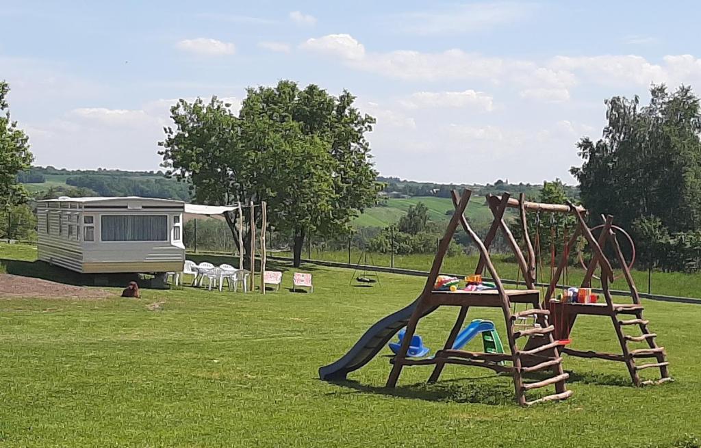 un parque infantil en un campo con una caravana en el fondo en Gosp. Agroturystyczne Stary Gaj, en Żerkowice