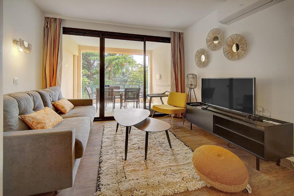 un salon avec un canapé et une télévision à écran plat dans l'établissement IMMOGROOM - 3 Rooms - Renovated - Pool - Air conditioning - Parking - Wifi, à Cannes
