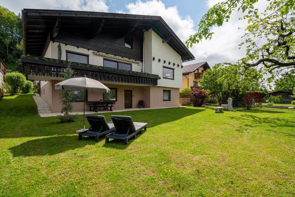 ein Haus mit zwei Stühlen und einem Sonnenschirm im Hof in der Unterkunft Haus Frank & Sophie in Feldkirchen in Kärnten