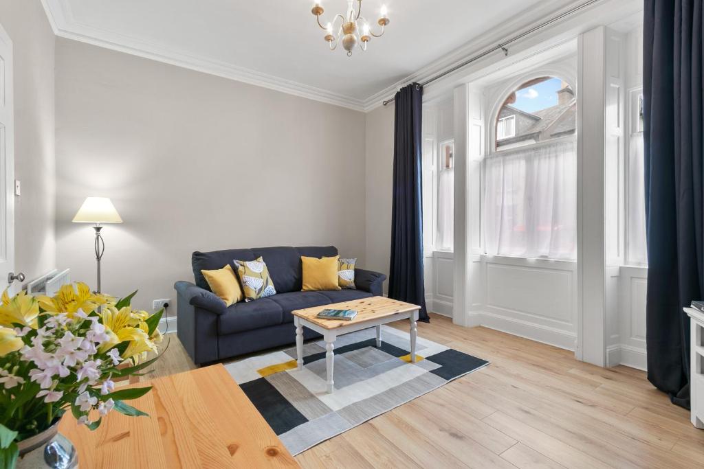 a living room with a blue couch and a table at Bay Apartment in Helensburgh