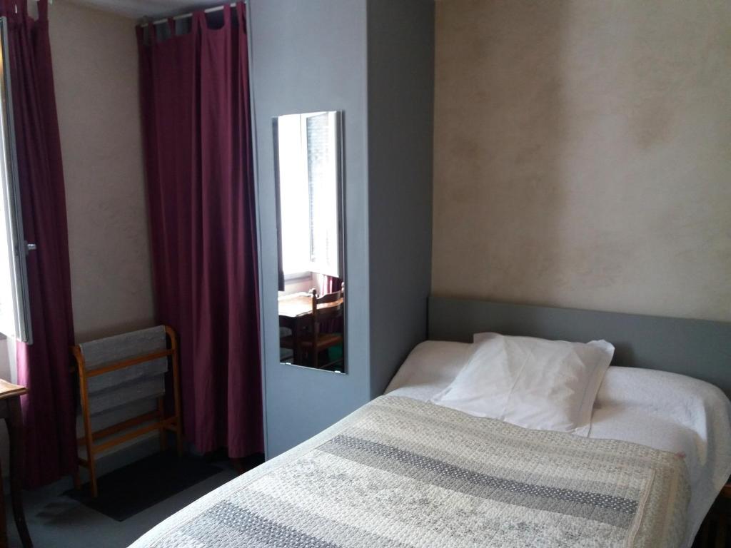 een kleine slaapkamer met een bed en een spiegel bij Hôtel Les Templiers in Luz-Saint-Sauveur