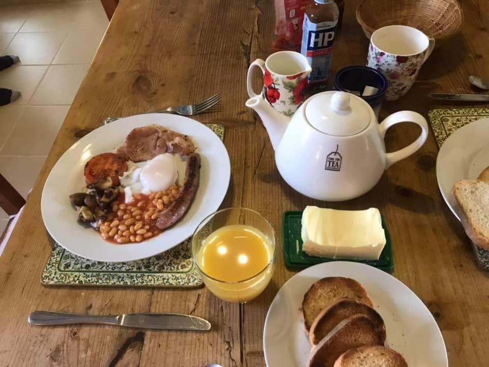 a table with plates of breakfast food and a teapot at Countryside B&B in Darnac