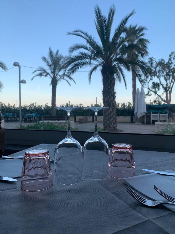 two wine glasses on a table with palm trees in the background at Hotel Svizzera in Arma di Taggia