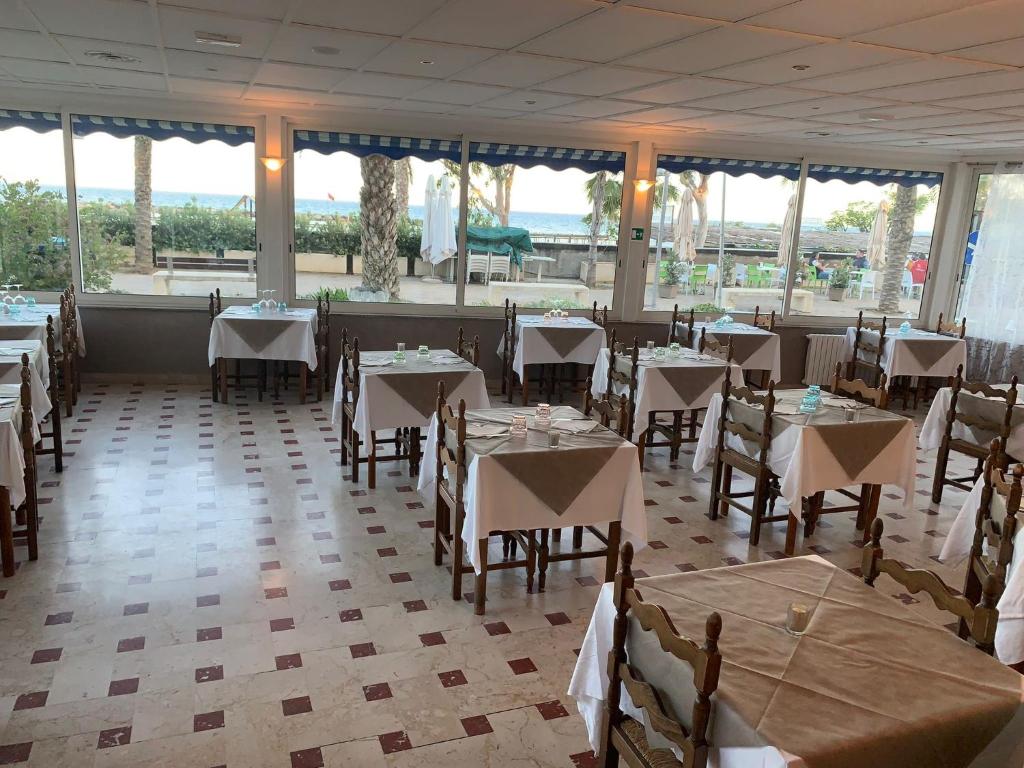 a dining room with tables and chairs and windows at Hotel Svizzera in Arma di Taggia