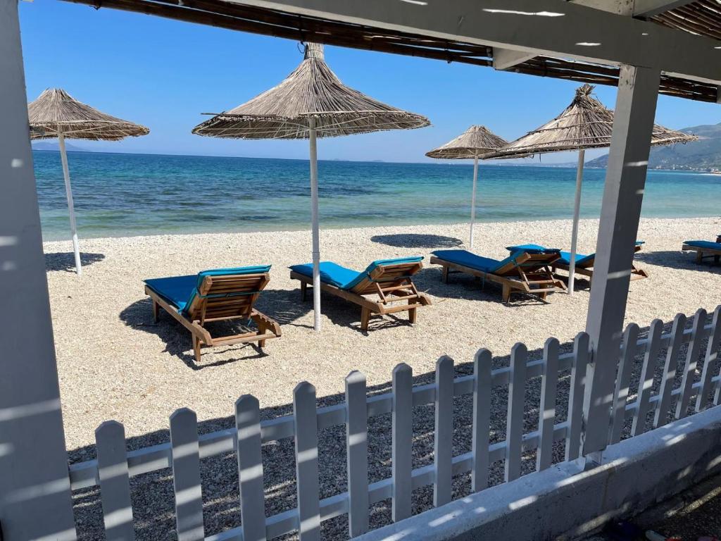 a beach with chairs and umbrellas and the ocean at Karaburun Sunset Beach in Orikum