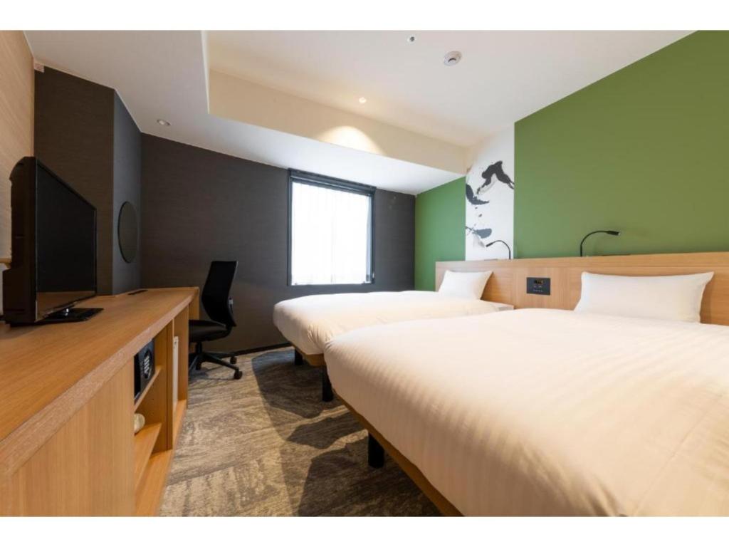 a hotel room with two beds and a flat screen tv at The OneFive Kyoto Shijo - Vacation STAY 41807v in Kyoto