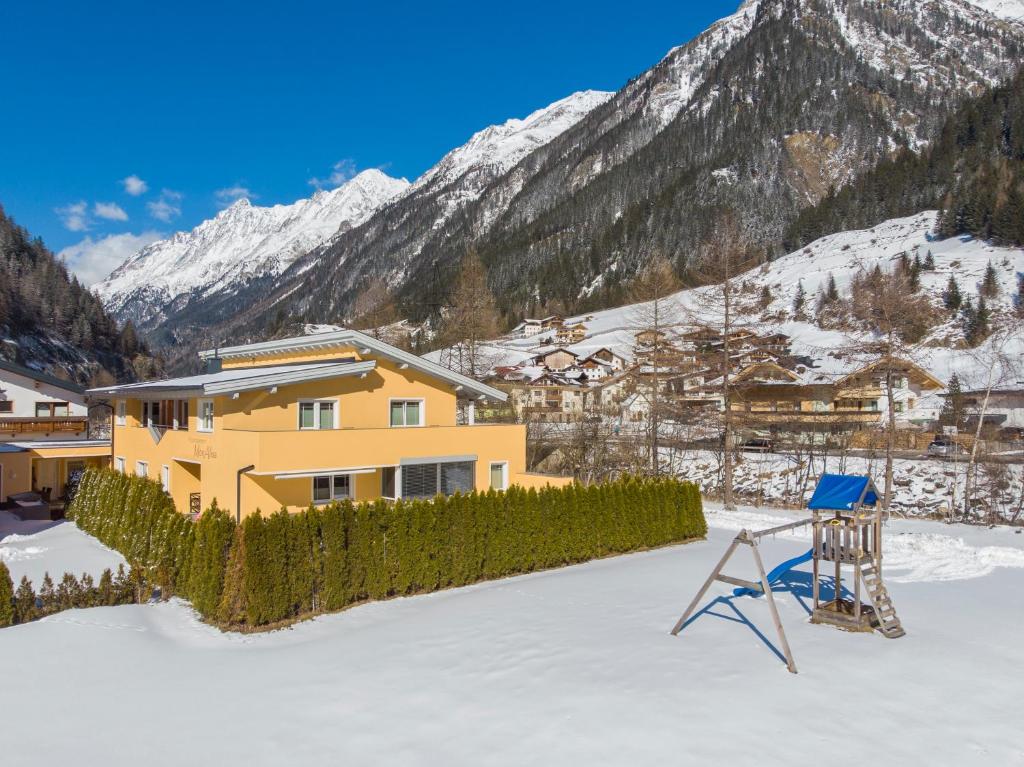 a yellow house in the snow with mountains at Appartement MonAlisa in Sölden