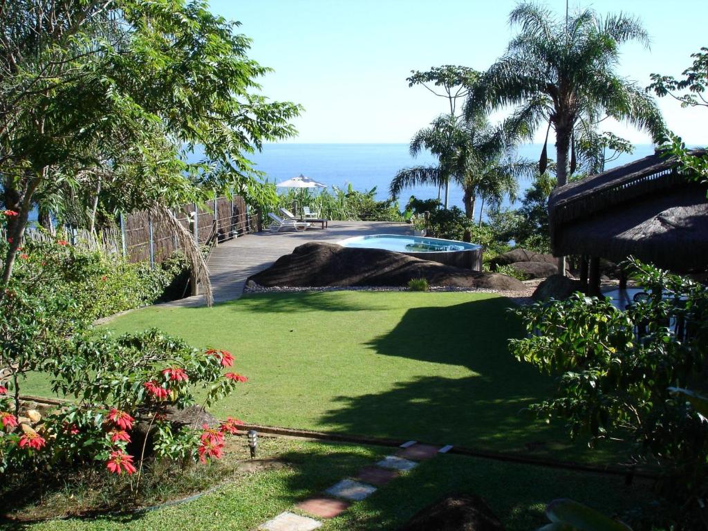 a garden with a swimming pool and the ocean in the background at Sítio Rodamonte in Ilhabela