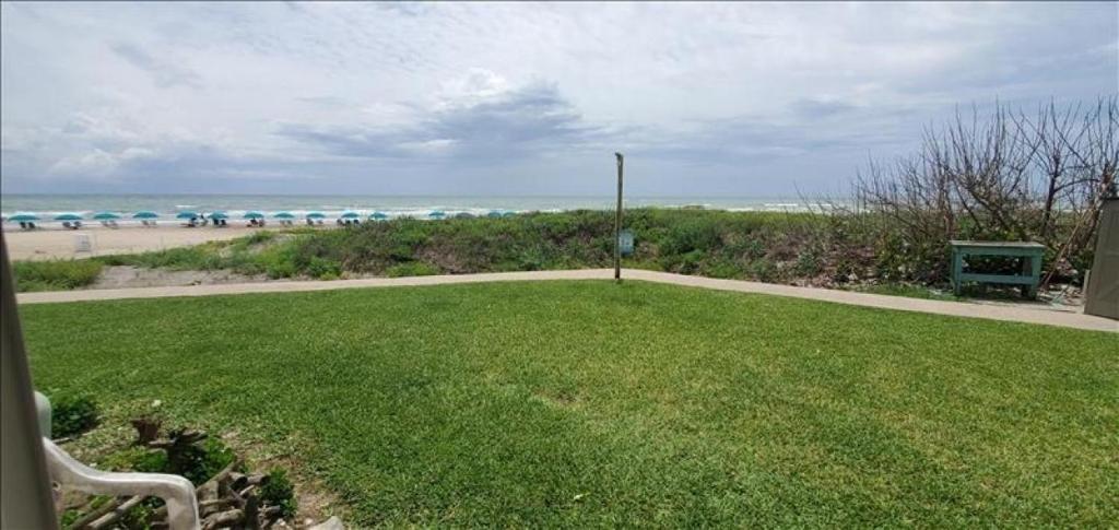a view of the beach from a lawn with a bench at La Internacional Condos O106 in South Padre Island
