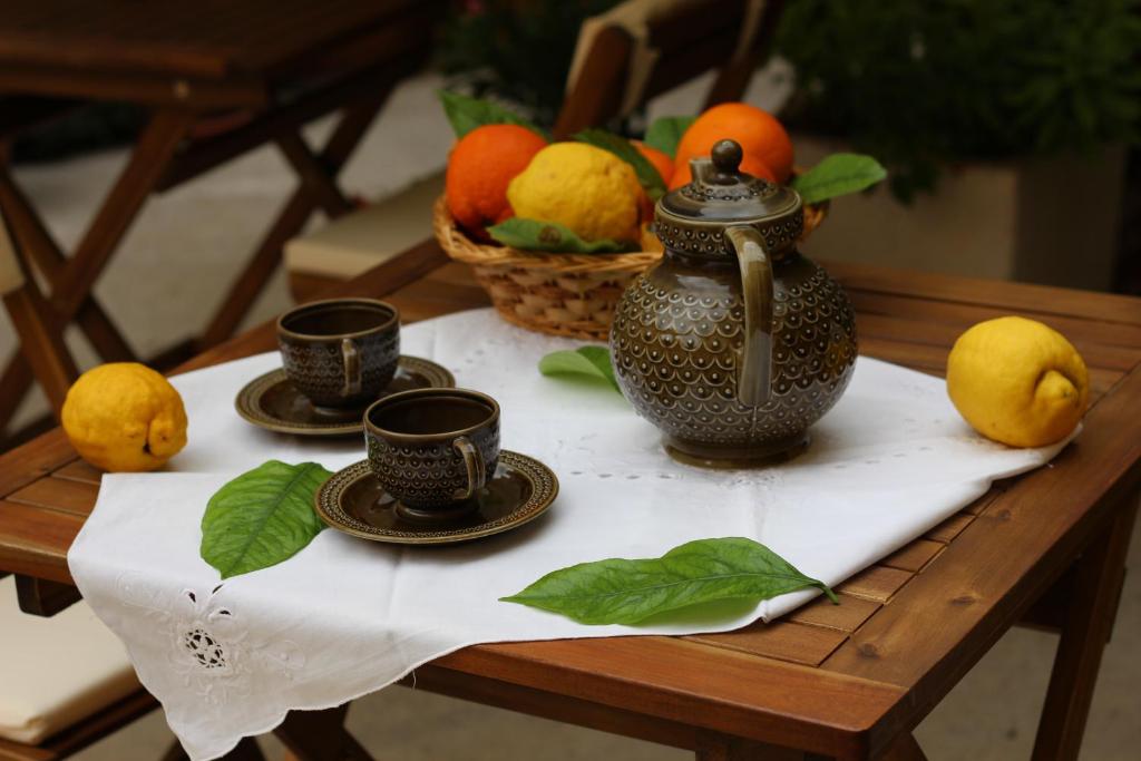 a table with two cups and a tea pot and fruit at Fiori e Limoni in Quartucciu