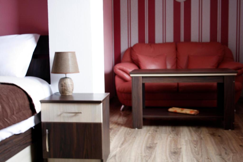 a bedroom with a red couch and a red chair at Guest House Bulgari in Kazanlŭk