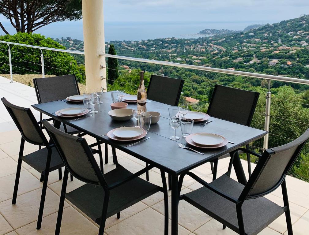 d'une table et de chaises noires sur le balcon. dans l'établissement Maison avec vue panoramique, à Cavalaire-sur-Mer