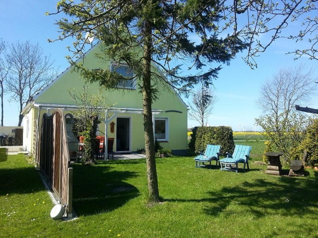 a green house with two benches in the yard at Haus Christine in Wremen