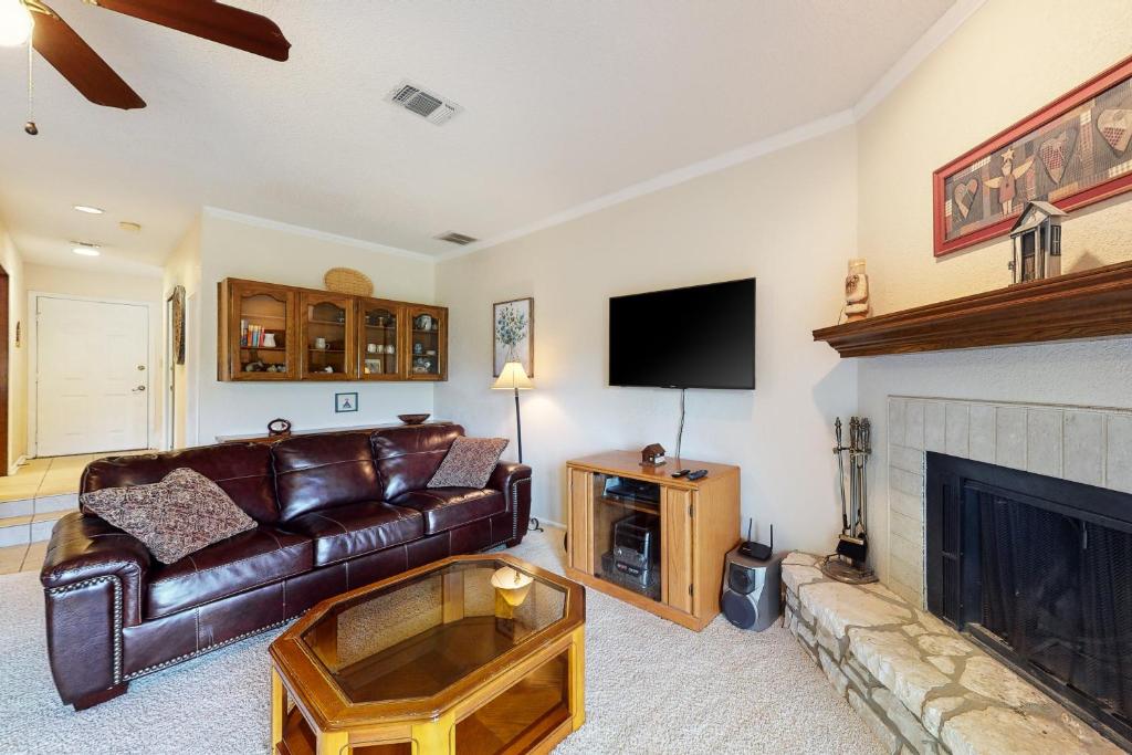 a living room with a leather couch and a fireplace at Condo on the Green in Canyon Lake
