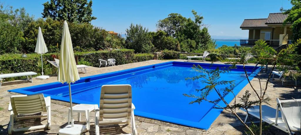 ein blauer Pool mit Stühlen und einem Sonnenschirm in der Unterkunft Navarro Hill Resort in Porto Santo Stefano