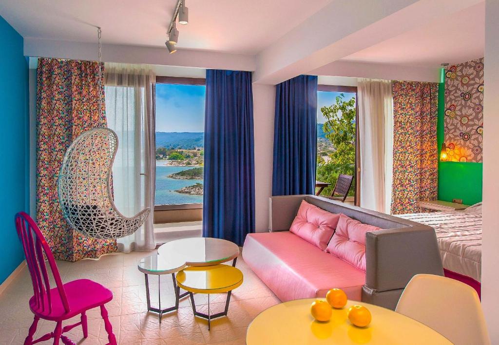 a living room with a pink couch and a bed at Thalassokipos in Vourvourou