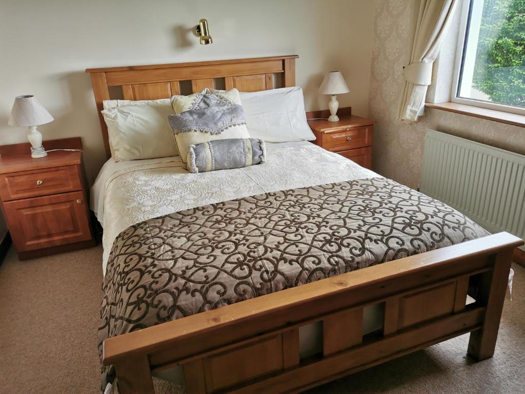 1 dormitorio con 1 cama grande y 2 mesitas de noche en Noraville House, en Killarney