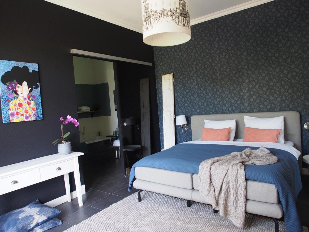 a bedroom with a bed with blue sheets and pink pillows at De oude dokterspraktijk in Zuidhorn