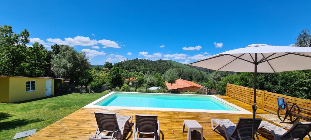 einen Pool mit Stühlen und einem Sonnenschirm in der Unterkunft casa de ramalhinha in Caldelas