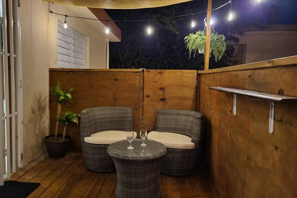 un patio con sillas de mimbre y una mesa con copas de vino en Relaxing Tropical Studio, en San Juan