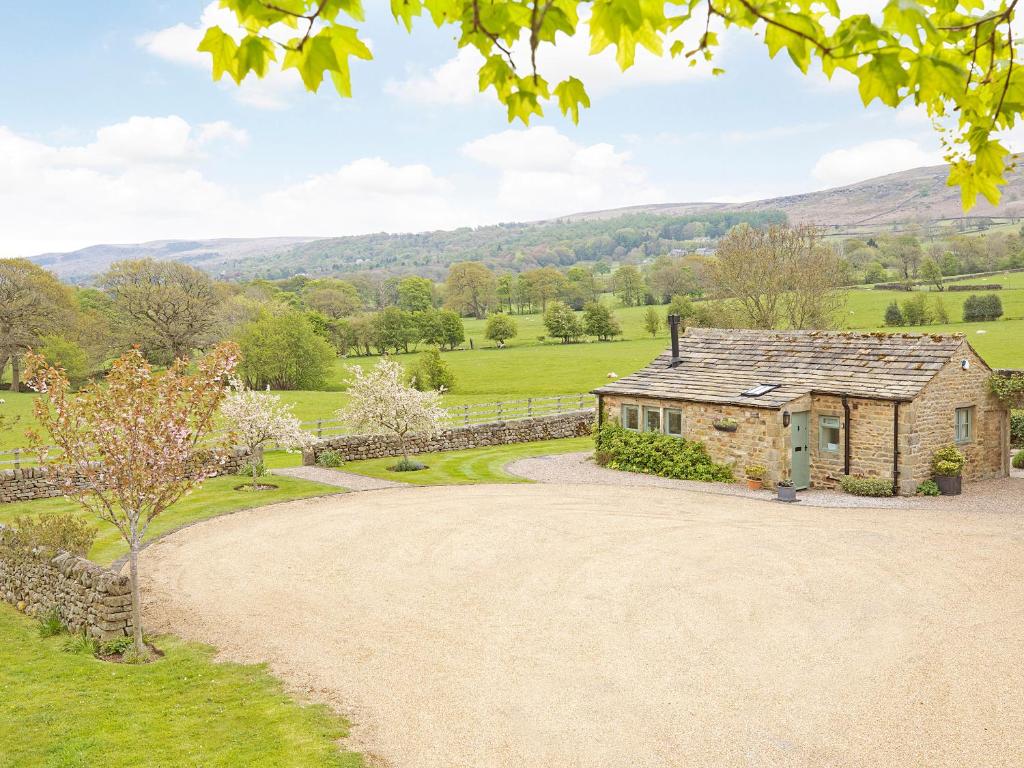 an exterior view of a stone house with a gravel driveway at Reynard Ing Cottage in Addingham