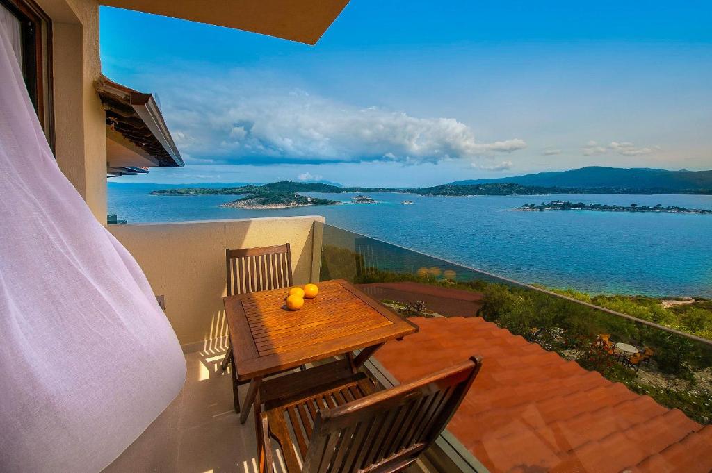 a balcony with a table and chairs with a view of the water at Thalassokipos in Vourvourou